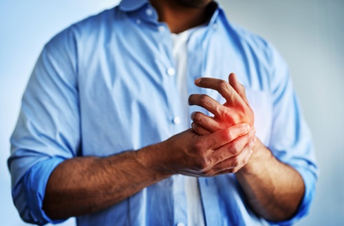 A man holds his hand, which is glowing red with pain.